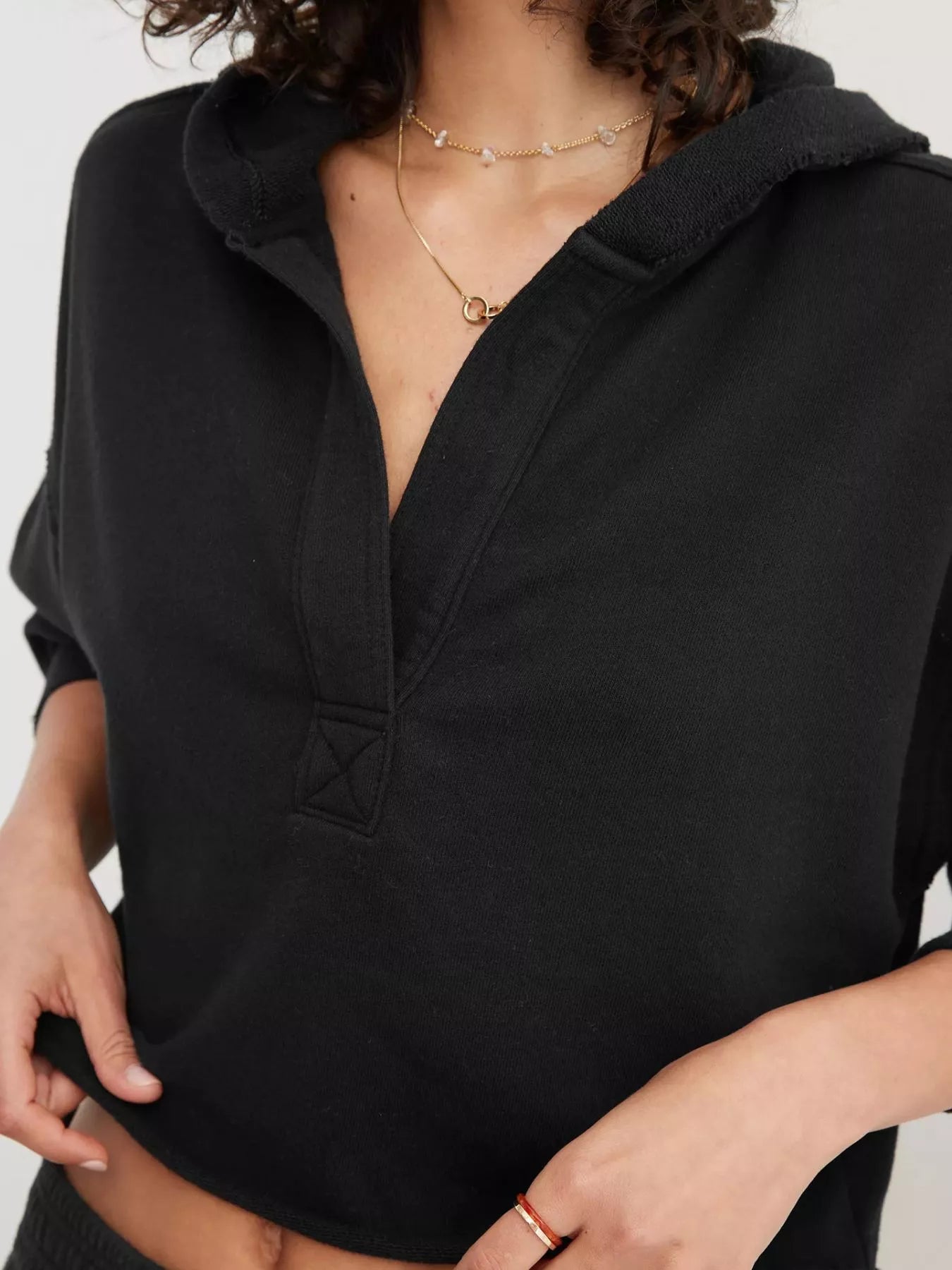 Exposed seam dropped shoulder hoodie in black with relaxed fit and v-neckline