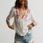 Embroidered floral V-neck blouse in white with red floral accents