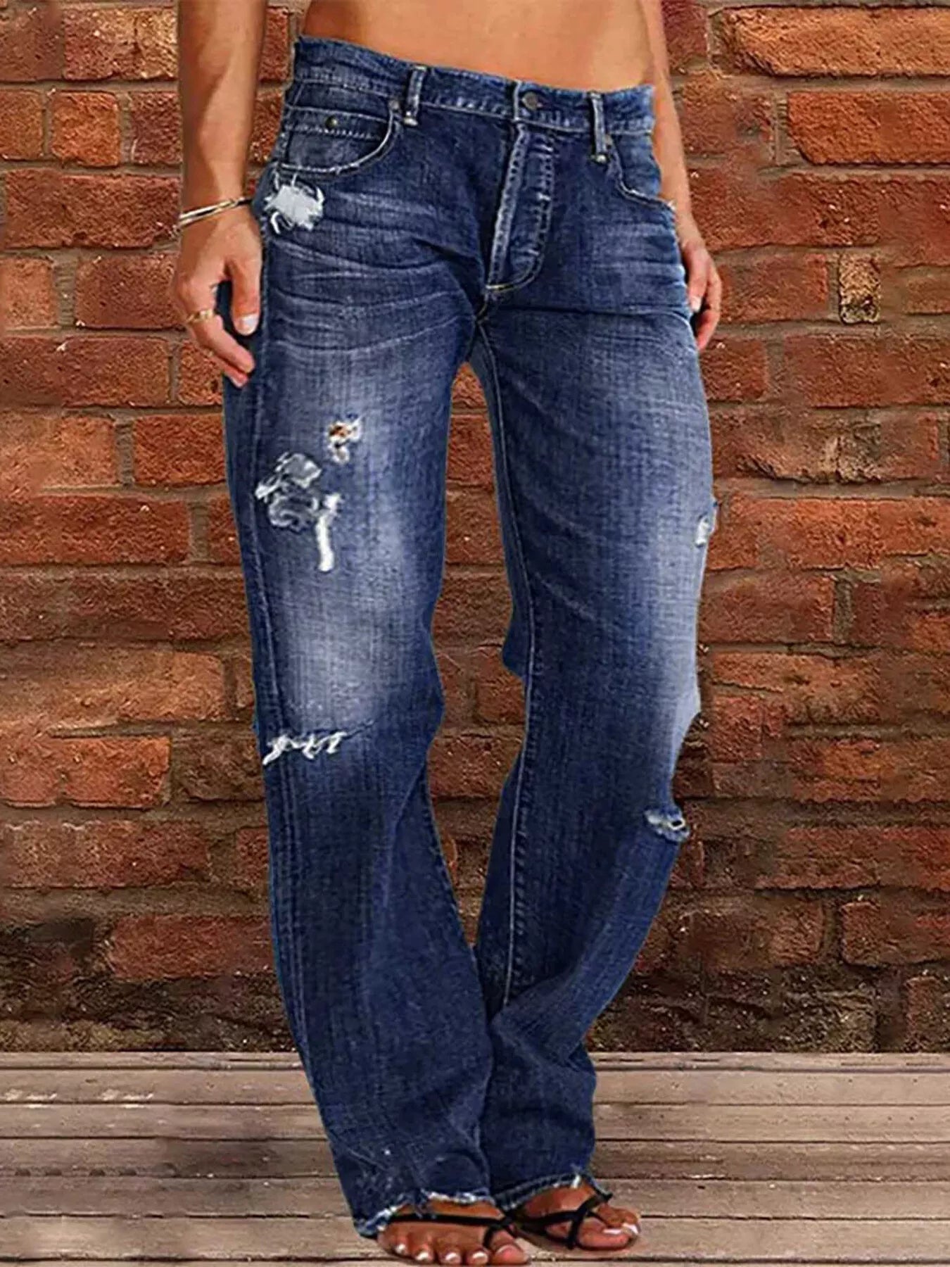 Distressed loose fit blue denim jeans with frayed hems and thigh rips
