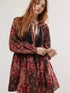 Woman in printed tie neck long sleeve boho mini dress with maroon brown motifs