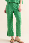 Green quilted linen pants with pockets, checkerboard pattern, and woven sandals