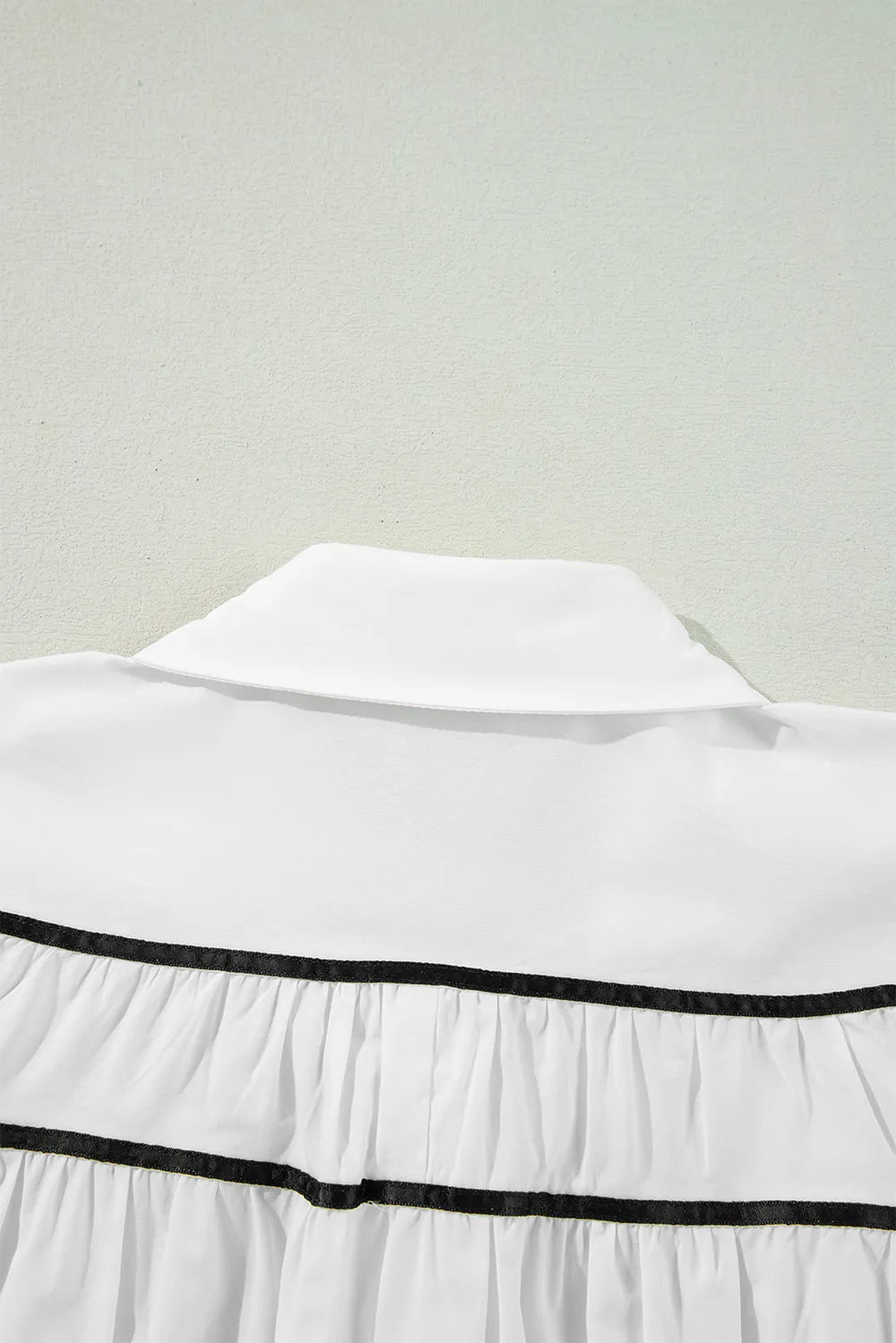 White ribbon bowtie collared blouse with black trim and ruffled tiers