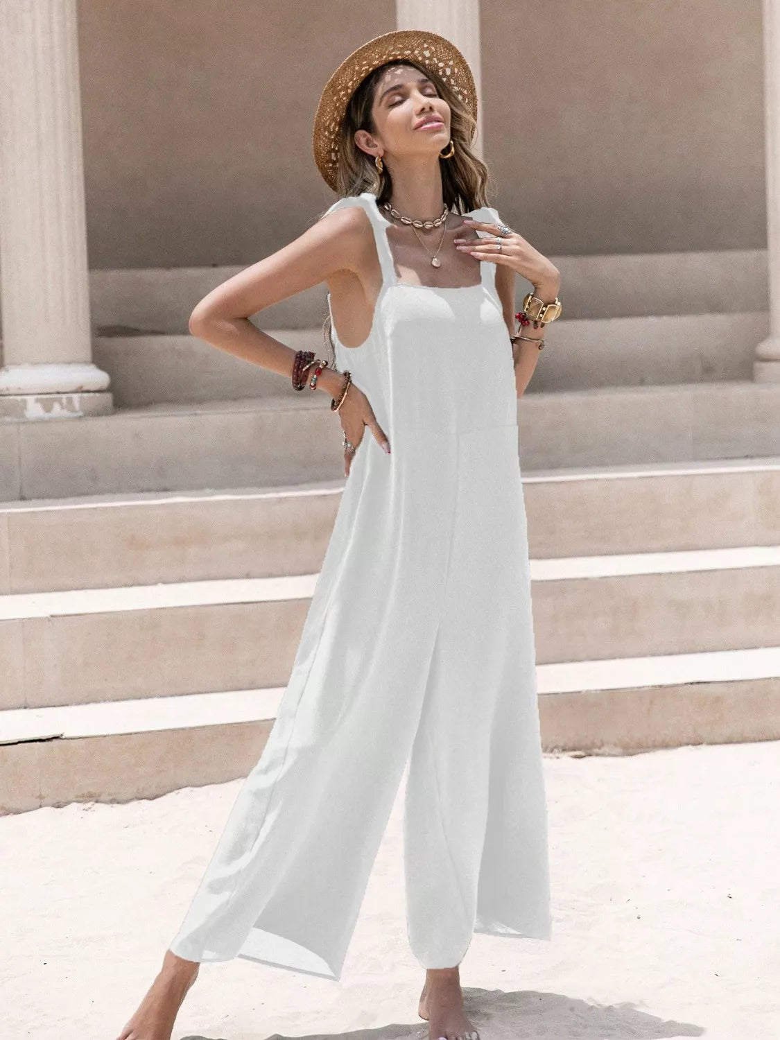 Model in flowing white sleeveless wide-leg jumpsuit with tie shoulders