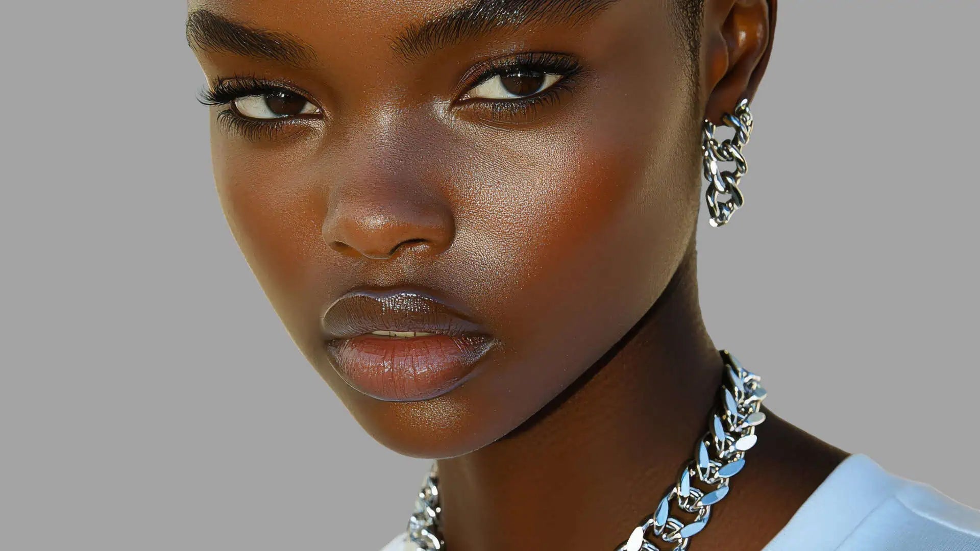 Close-up of a woman wearing silver earrings and a necklace against a gray background