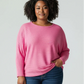 Woman wearing a pink sweater and blue jeans on a white background